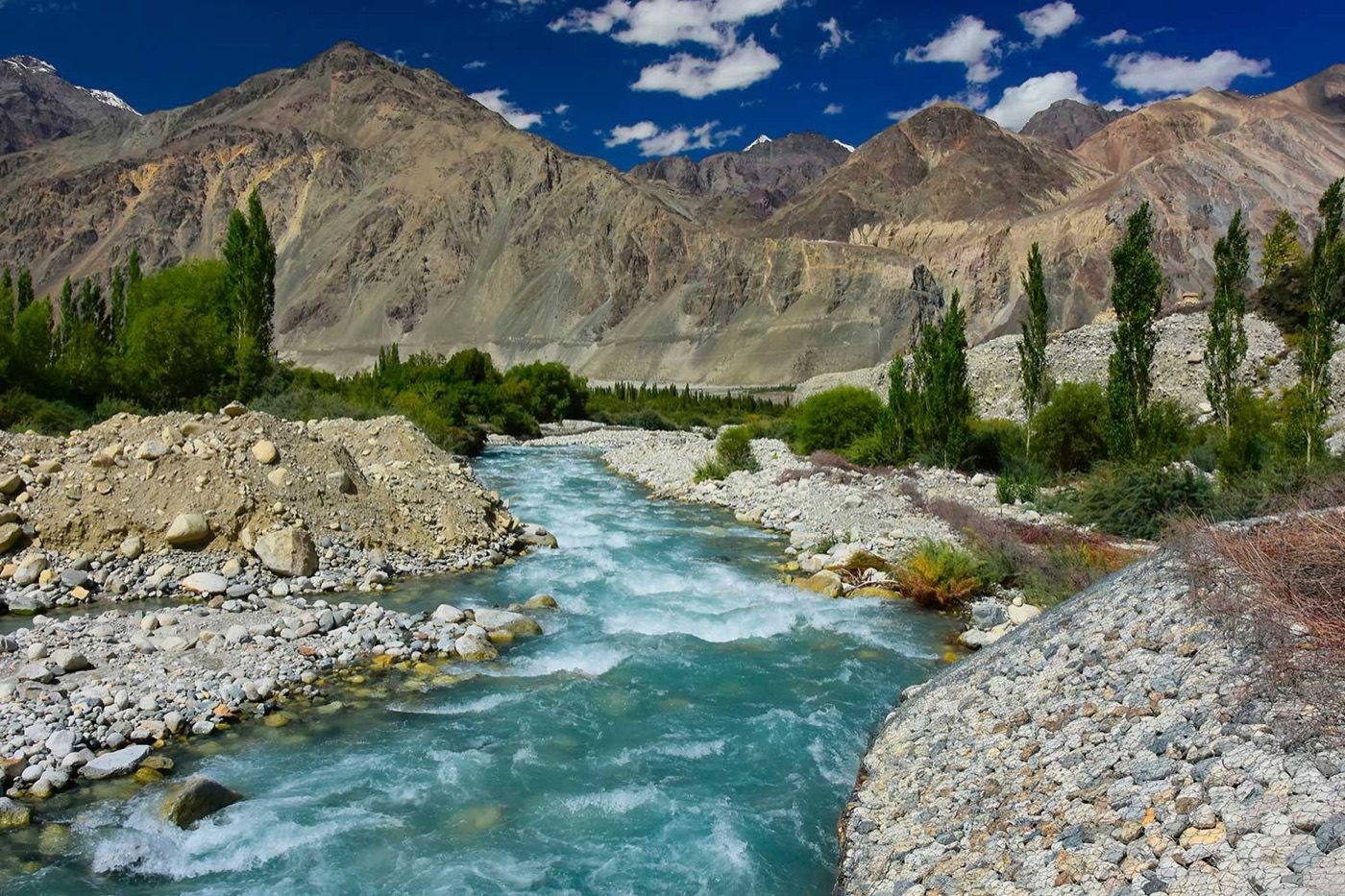 A bright turquoise river running through a stony Changthang valley